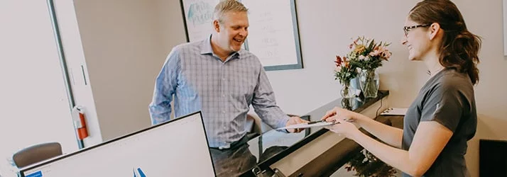 A receptionist welcoming a patient at the front desk
